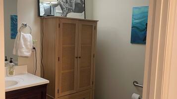 A bathroom with a wooden cabinet, a sink, a toilet, and a mirror.