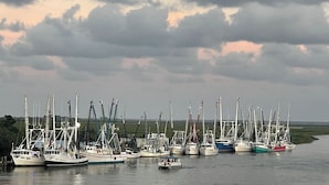 A marina with multiple boats docked, a small boat in the water, and a cloudy sky with a visible moon. - Walk to waterfront dining, shops, wine bar. 2 miles from I-95. No pet fee! (Darien)