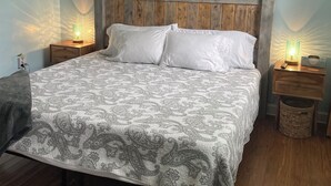 A bedroom with a wooden headboard, a bed with white linens, two bedside tables with lamps, a framed fish picture on the wall, and a ceiling fan. - Walk to waterfront dining, shops, wine bar. 2 miles from I-95. No pet fee! (Darien)