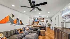Una sala de estar moderna con un sofá modular, una mesa de centro redonda y un ventilador de techo.