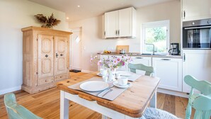 Una cucina moderna con mobili bianchi, un tavolo da pranzo in legno apparecchiato con piatti e posate, e un vaso con fiori.