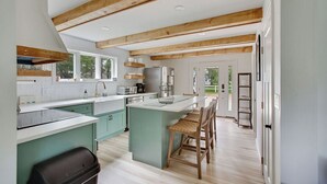 A modern kitchen with wooden beams, a central island, and a view to the outside. - Pet Friendly-Updated Goose Rocks Beach Oasis! (Kennebunkport)