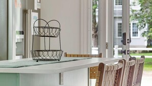 A kitchen with a white countertop, a two-tiered wire basket, and wooden chairs. - Pet Friendly-Updated Goose Rocks Beach Oasis! (Kennebunkport)
