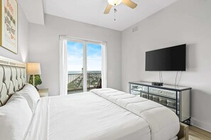 Ein Schlafzimmer mit Bett, Fernseher, Balkon und Deckenventilator.