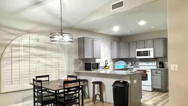 A modern kitchen with grey cabinets, a central island, and a dining area with a table and chairs. - Upgraded entire residential home (Scottsdale)