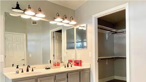 A bathroom with a large mirror, vanity, and a walk-in closet. - Upgraded entire residential home (Scottsdale)