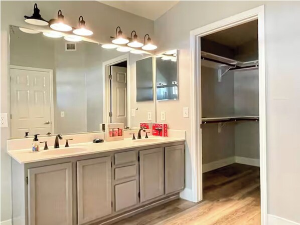 A bathroom with a large mirror, vanity, and a walk-in closet. - Upgraded entire residential home (Scottsdale)