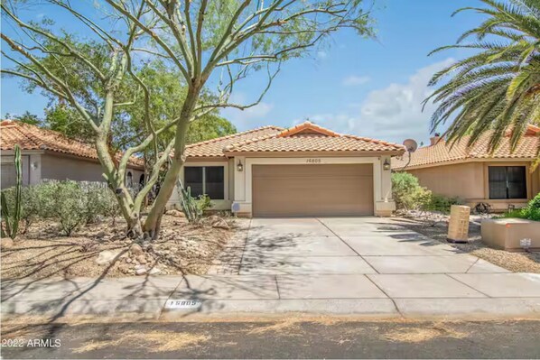 Stucco home with a garage and landscaped garden.