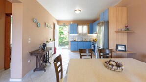 Une cuisine moderne avec des meubles bleus, une table à manger avec des chaises et une vue sur l’extérieur.