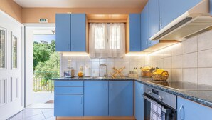 Une cuisine moderne avec des meubles bleus, un four encastré et une fenêtre avec un rideau.