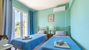 Une chambre avec deux lits, une chaise, une petite table et une fenêtre avec des rideaux.