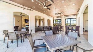 Un espacio interior amplio con varios conjuntos de asientos, mesas y sillas, y una cocina al fondo.