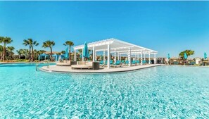 A clear blue pool with a white gazebo and lounge chairs.