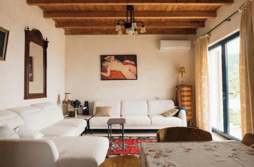Una sala de estar con un sofá blanco, un tapete rojo y un cuadro en la pared.