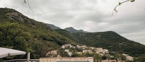 A rooftop infinity pool with a view of a hillside village.
