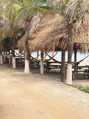 A beach with thatched umbrellas and wooden benches. - Oasis Paradise Hotel (Tela)