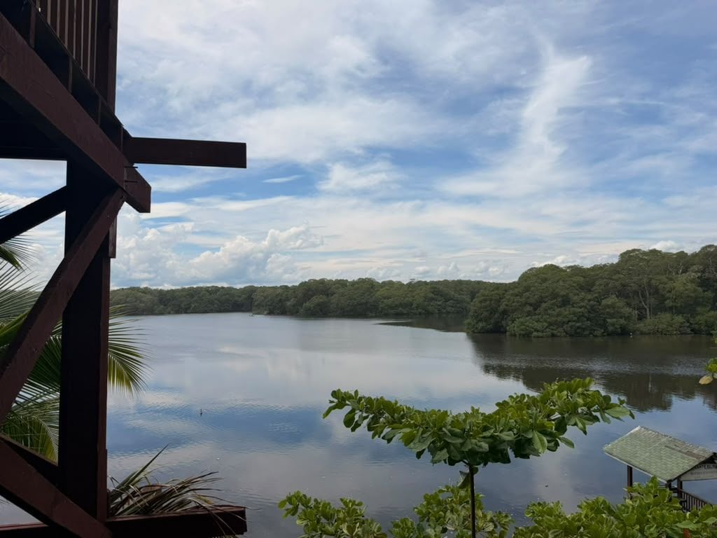 Blick auf einen See mit einer hölzernen Struktur im Vordergrund, vermutlich ein Teil eines Hotels oder Resorts.