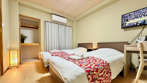 Una habitación de hotel con cama, escritorio, silla, aire acondicionado y televisor.