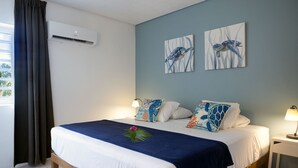 A double bed with a white and navy blue bedspread, two matching pillows, and a small table with a lamp beside it. - Divers Paradise 6, Divers paradise apartment with Ocean view!  (Kralendijk)