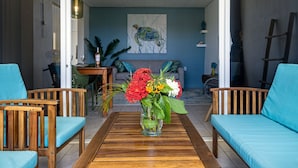 A living room with a wooden coffee table, two blue sofas, and a glass vase with flowers. - Divers Paradise 6, Divers paradise apartment with Ocean view!  (Kralendijk)