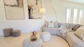 Un salon moderne avec un canapé gris, des poufs ronds et des œuvres d’art abstraites accrochées au mur.