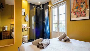 Ein Hotelzimmer mit Bett, Dusche, Fenster und einem Poster an der Wand.
