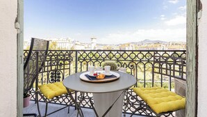 Ein Balkon mit Tisch, gedeckt für zwei Personen, mit einem Croissant, einer Tasse und einem Untertasse.