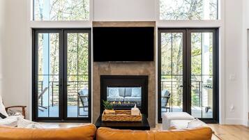 A living room with a fireplace, large windows, and a view of the outdoors.