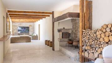 A spacious living area with a stone fireplace, wooden beams, and a stone wall.