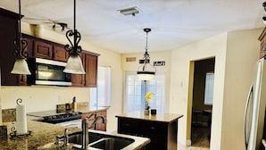 Cocina con encimeras de granito, electrodomésticos de acero inoxidable y armarios de madera.