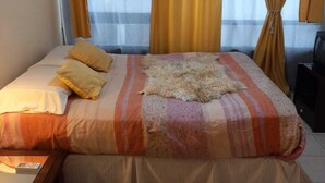 A hotel room with a bed, curtains, an air conditioning unit, and a window. - Porteño Heart Santa Fe and Cerrito (Buenos Aires)