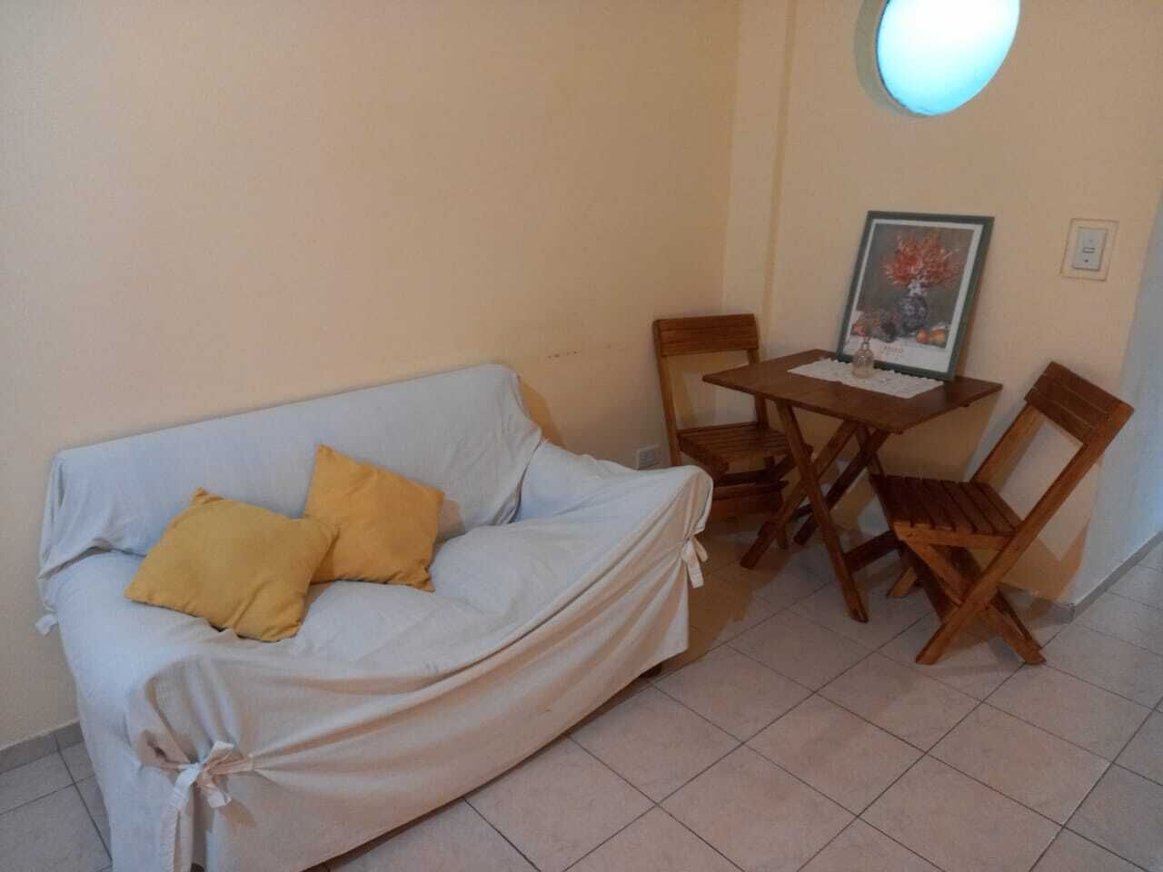 Una habitación con un sofá tapizado, una mesa de madera y dos sillas.