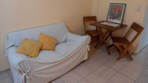 A room with a covered sofa, a wooden table, and two chairs. - Porteño Heart Santa Fe and Cerrito (Buenos Aires)