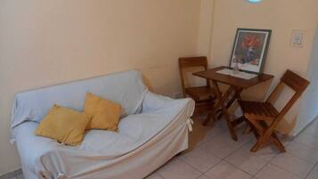 Una habitación con un sofá tapizado, una mesa de madera y dos sillas.