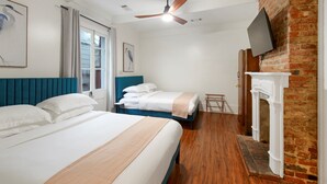 Une chambre d’hôtel avec deux lits, une cheminée, un téléviseur fixé à un mur en briques et un ventilateur de plafond.