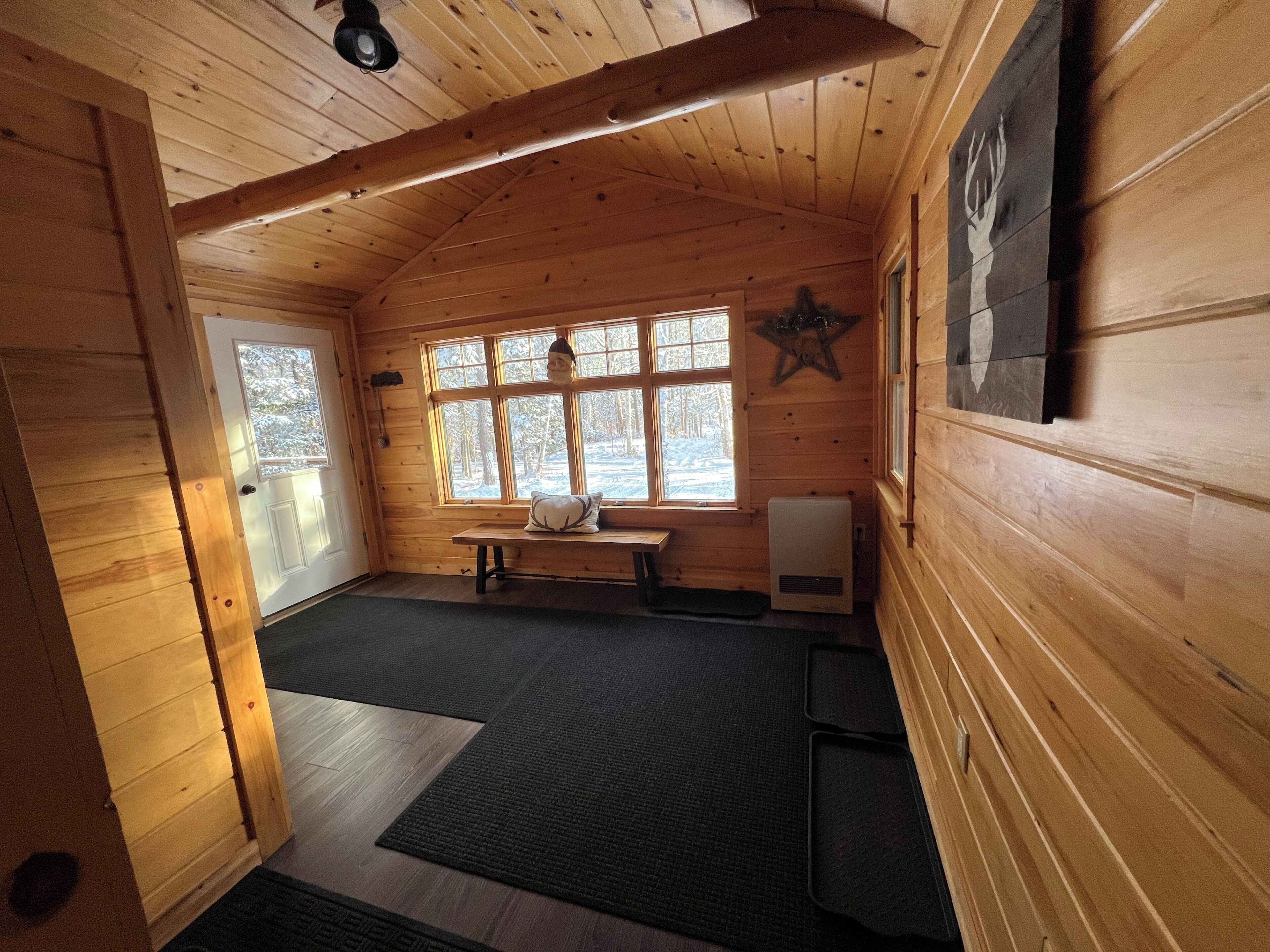Ein Holzhütten-Interieur mit Holzwänden, einer Bank, einem Fenster mit Sterndekoration und einer Tür.