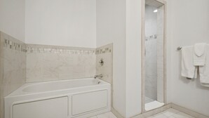 A modern bathroom with a bathtub, a shower enclosure, and a tiled floor.