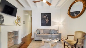 A living room with a sofa, armchair, coffee table, fireplace, TV, and artwork.