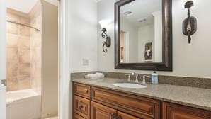 Un ba ño con bañera, lavabo con dispensador de jabón y armarios de madera.