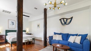 Una habitación con una cama, un sofá azul, una mesa de centro de madera y una lámpara de araña.