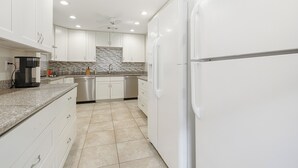 Una cocina moderna con armarios blancos, un lavavajillas de acero inoxidable y un refrigerador blanco.