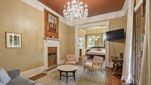 A living room with a fireplace, a chandelier, and a television mounted on the wall.