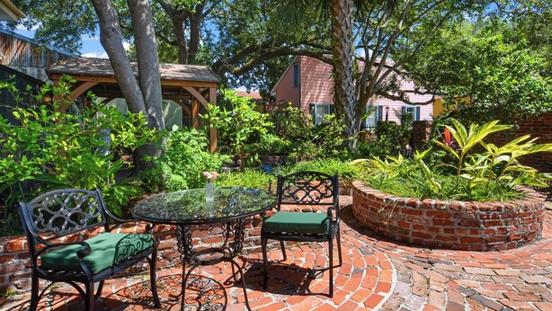 A patio with a glass table, two chairs, and a brick planter.