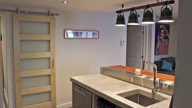 Een moderne keuken met een houten schuifdeur, een roestvrijstalen spoelbak en hanglampen.
