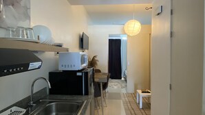 Una cocina compacta con microondas, lavamanos y un pequeño comedor.