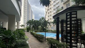 Un edificio residencial con piscina, rodeado de vegetación y una zona de estar cubierta.