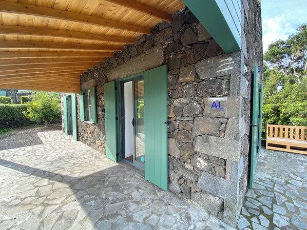 Un bâtiment en pierre avec des volets verts et un plafond en bois.