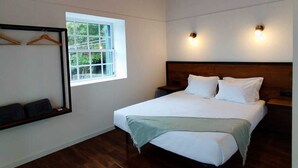 A bedroom with a wooden ceiling, a large bed, a window, and wall-mounted lights. - Refúgio da Montanha (Sao Roque do Pico)