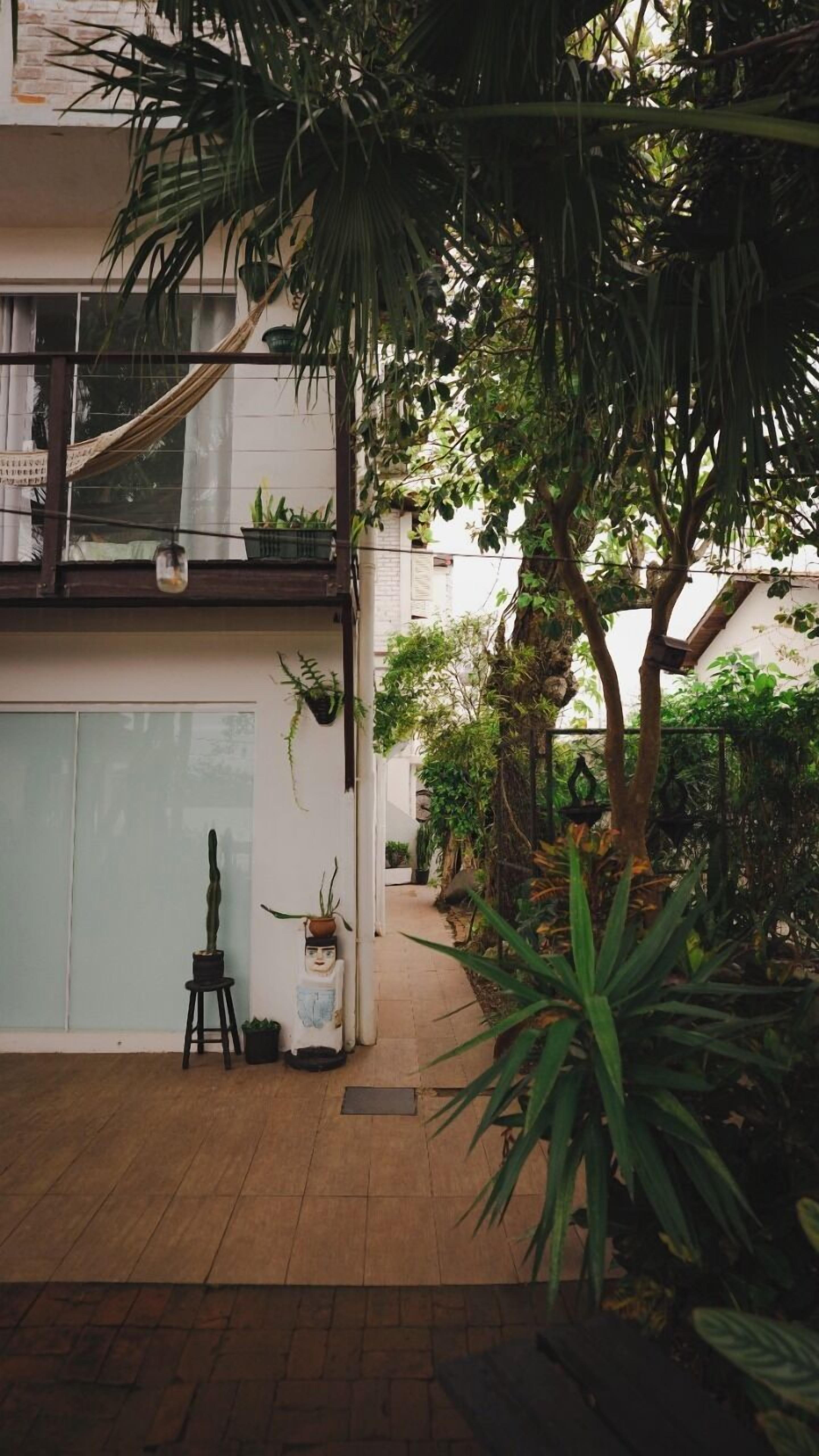 A courtyard with a wooden floor, potted plants, and a hammock.