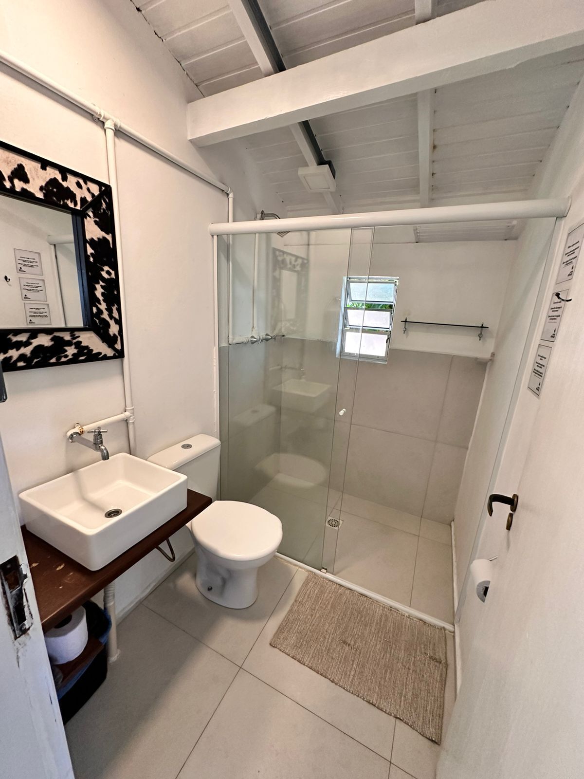 Un baño moderno con ducha de vidrio, lavamanos blanco y retrete.